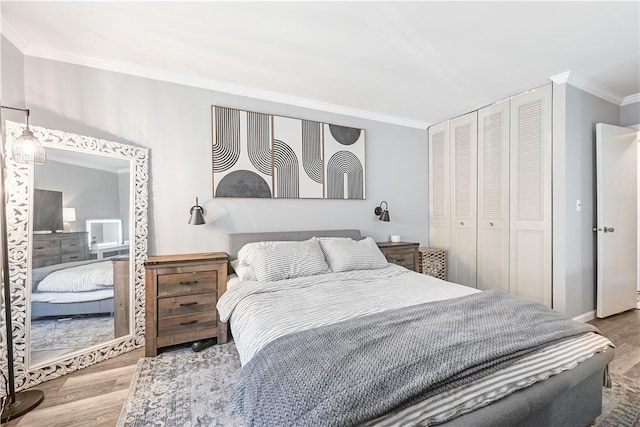 bedroom with hardwood / wood-style flooring, ornamental molding, and a closet