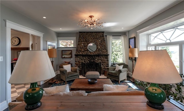 living room with a stone fireplace and a notable chandelier