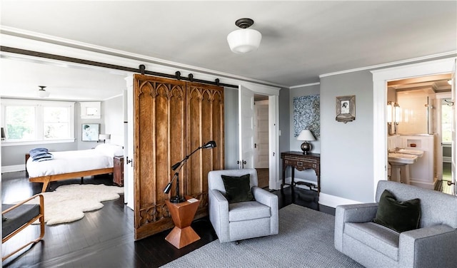 living area featuring a barn door, ornamental molding, a healthy amount of sunlight, and wood-type flooring