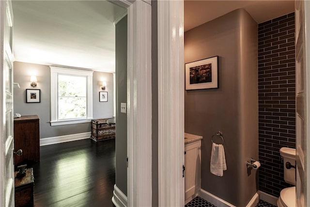 bathroom with hardwood / wood-style floors, vanity, brick wall, and toilet