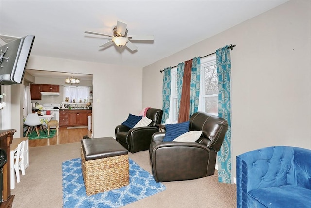 living room featuring ceiling fan with notable chandelier and light colored carpet