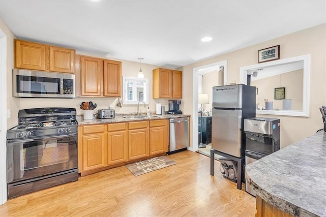 kitchen with hanging light fixtures, sink, light hardwood / wood-style floors, and appliances with stainless steel finishes