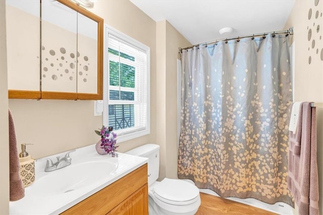 bathroom with plenty of natural light, vanity, hardwood / wood-style floors, and toilet