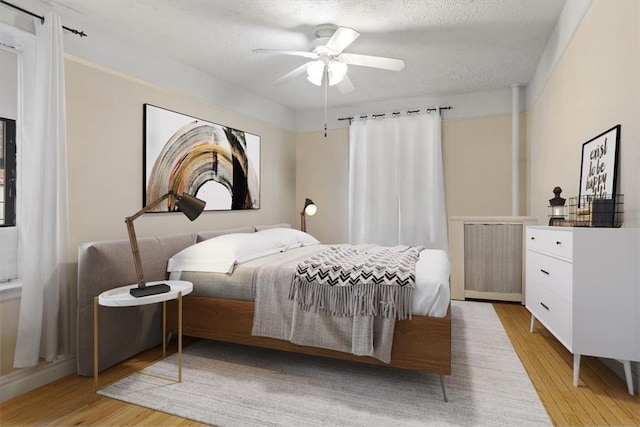 bedroom with ceiling fan, light hardwood / wood-style floors, and a textured ceiling