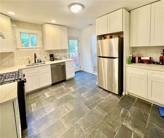 kitchen with white cabinetry, sink, light stone countertops, tasteful backsplash, and appliances with stainless steel finishes