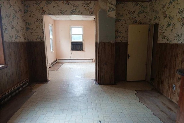 empty room featuring wooden walls and a baseboard radiator