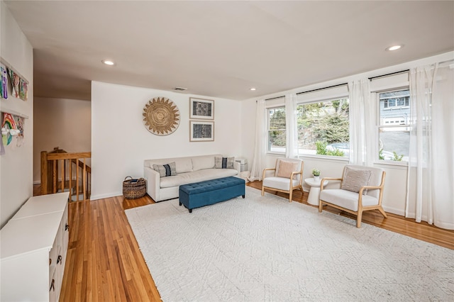 living room featuring light wood finished floors, visible vents, recessed lighting, and baseboards