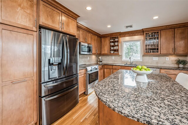 kitchen featuring a sink, dark stone countertops, brown cabinets, and stainless steel appliances