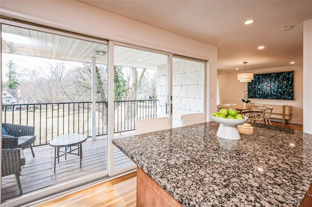 kitchen featuring hanging light fixtures, recessed lighting, dark stone counters, and light wood-type flooring