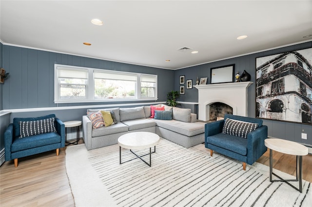 living room featuring visible vents, crown molding, baseboard heating, a fireplace, and wood finished floors