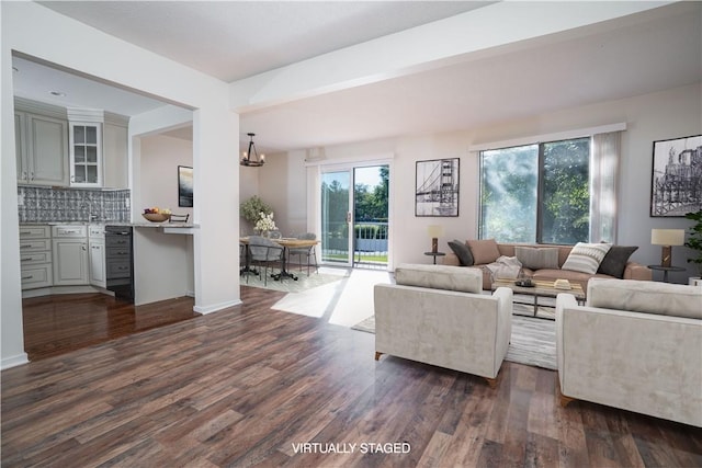 living room with beam ceiling, an inviting chandelier, and dark wood-type flooring