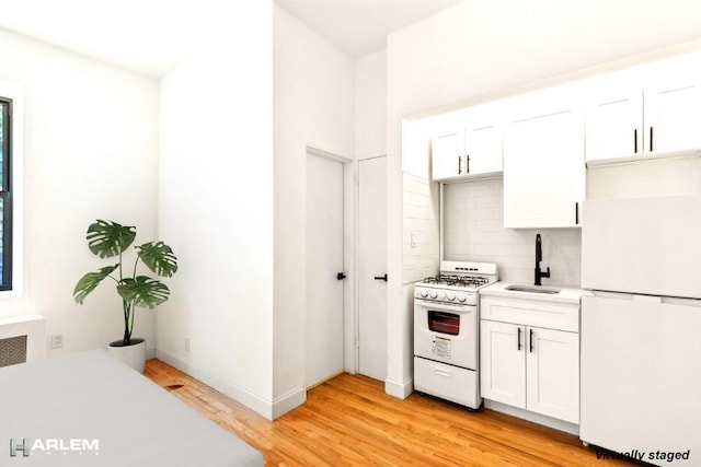 kitchen with white appliances, backsplash, white cabinets, sink, and light wood-type flooring