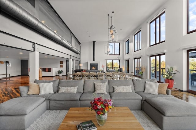 living room featuring wood-type flooring, a towering ceiling, and a fireplace