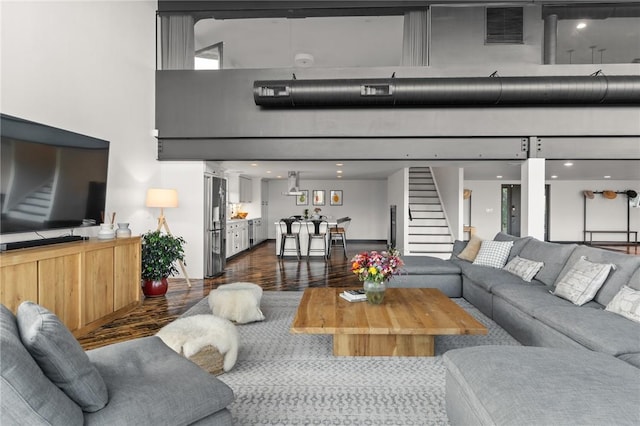 living room featuring a towering ceiling and dark wood-type flooring