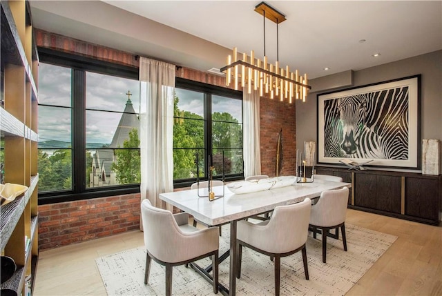 dining room featuring a chandelier, brick wall, and light hardwood / wood-style flooring