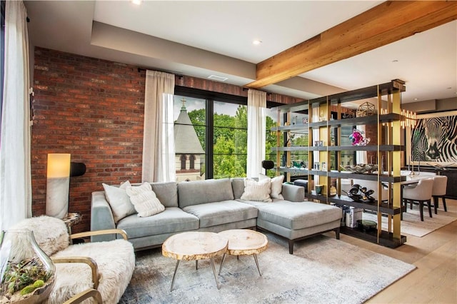 living room featuring beamed ceiling, brick wall, and hardwood / wood-style flooring