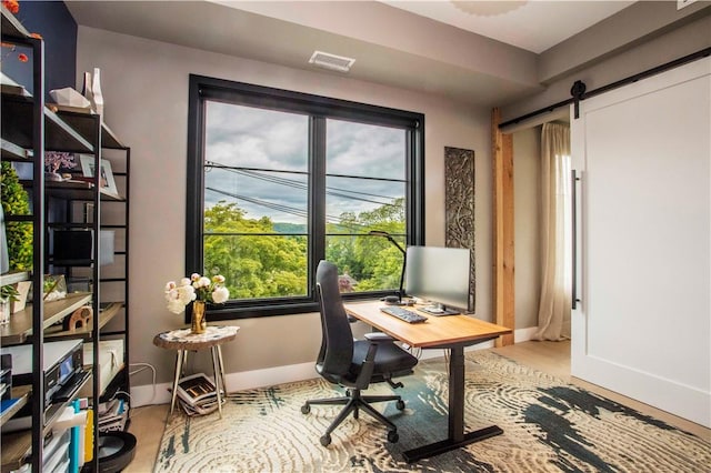 home office with wood-type flooring and a barn door