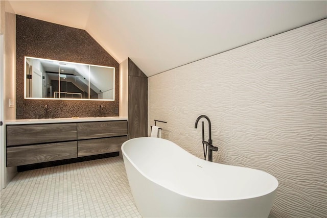 bathroom with vanity, a tub, and vaulted ceiling