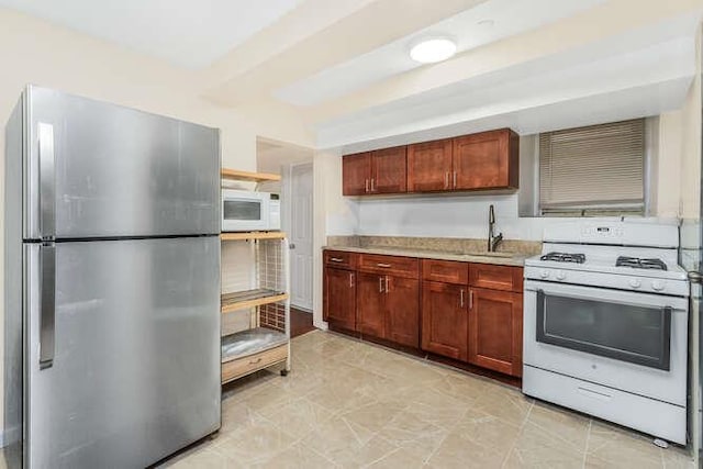 kitchen with beamed ceiling, white appliances, and sink