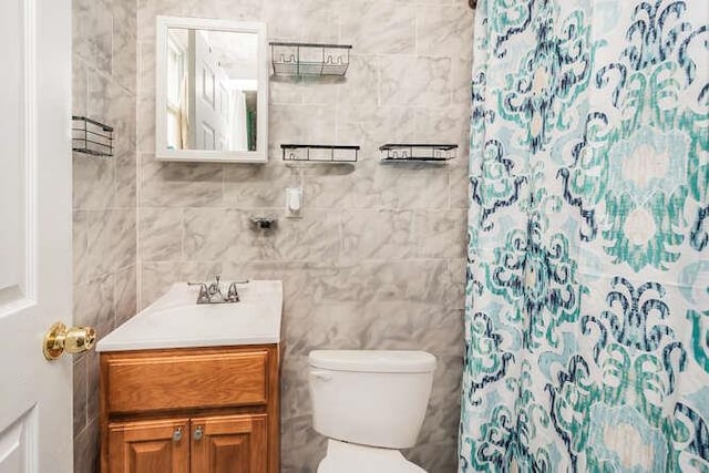 bathroom with toilet, vanity, tile walls, and a shower with shower curtain