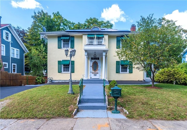 view of front facade featuring a balcony and a front yard