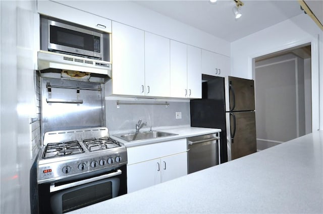 kitchen with decorative backsplash, appliances with stainless steel finishes, ventilation hood, sink, and white cabinetry