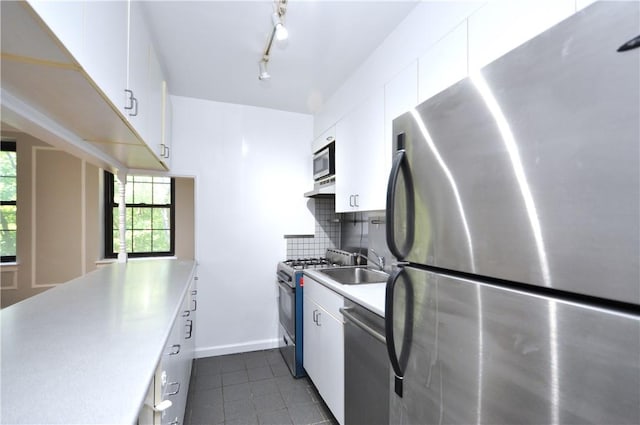 kitchen featuring white cabinets, stainless steel appliances, dark tile patterned flooring, and tasteful backsplash