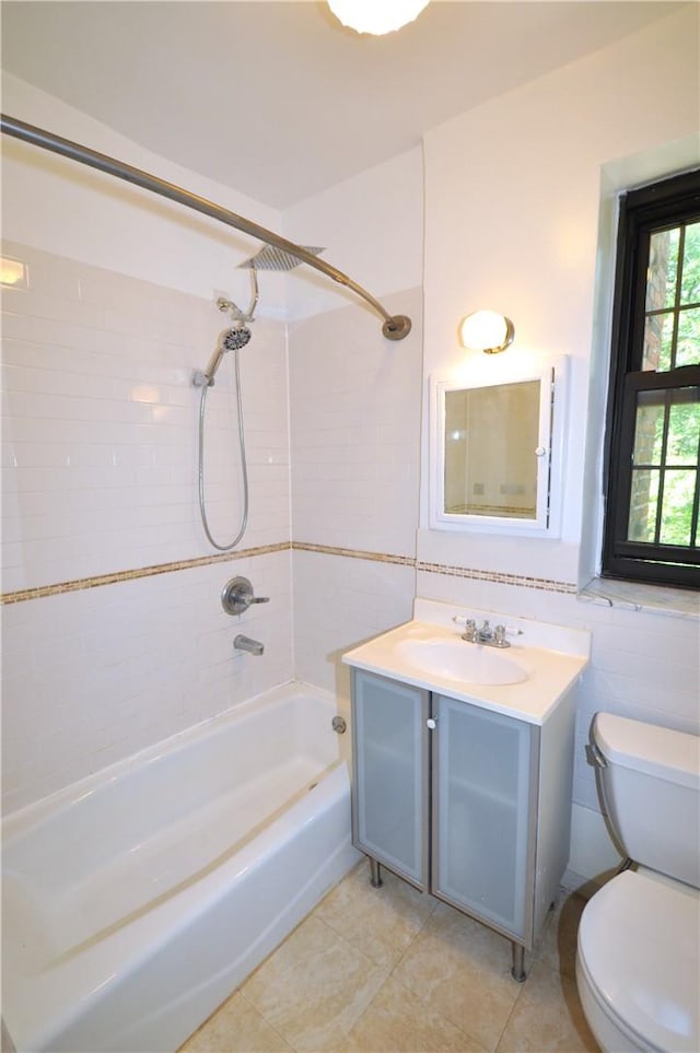 full bathroom featuring vanity, tile patterned flooring, tiled shower / bath combo, toilet, and tile walls