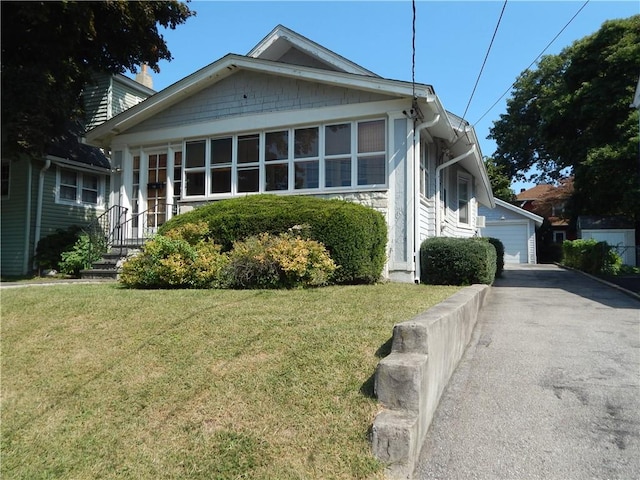 view of front of property with a front yard, a garage, and an outdoor structure