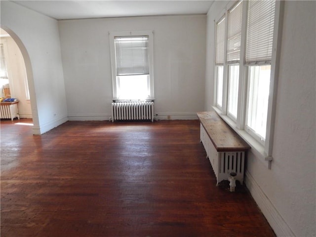 empty room featuring radiator heating unit and dark hardwood / wood-style floors