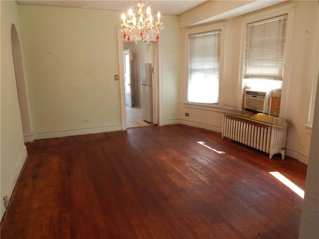 unfurnished room with hardwood / wood-style flooring, cooling unit, radiator, and a chandelier