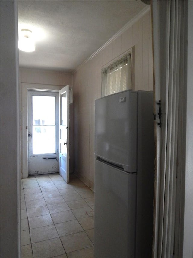 kitchen featuring light tile patterned flooring, ornamental molding, and stainless steel refrigerator