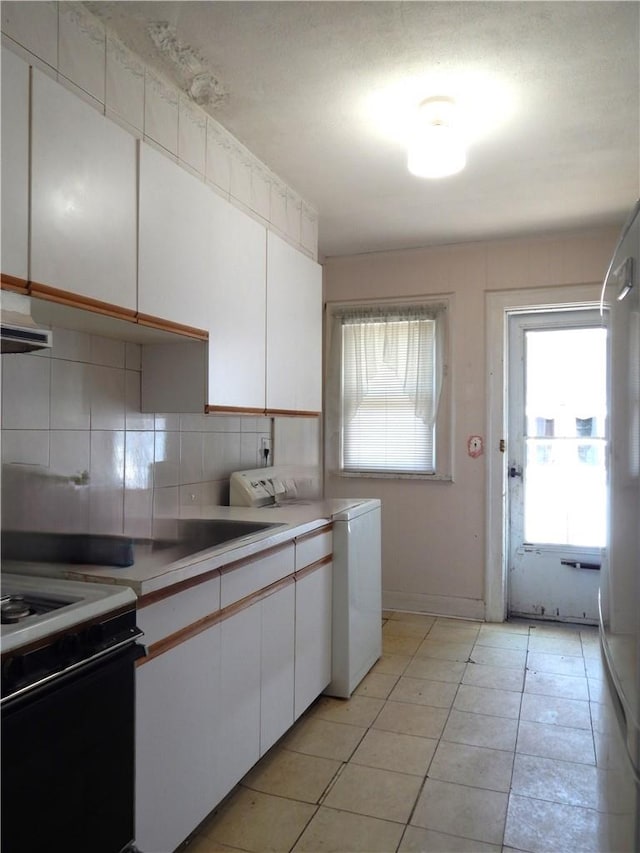 kitchen featuring white range with electric cooktop, white cabinetry, washer / clothes dryer, and tasteful backsplash