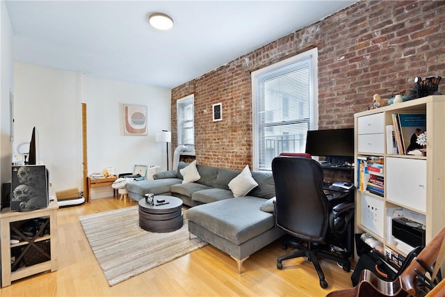 home office with light wood-type flooring and brick wall