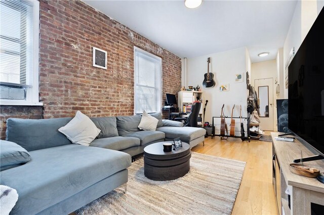 living room featuring light wood-type flooring and brick wall