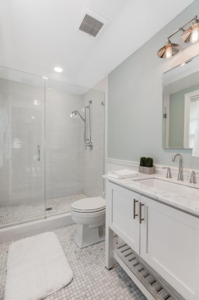 bathroom with a shower with door, vanity, tile patterned floors, and toilet