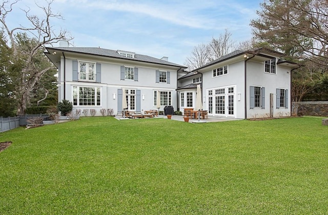 rear view of property featuring french doors, a patio, and a lawn