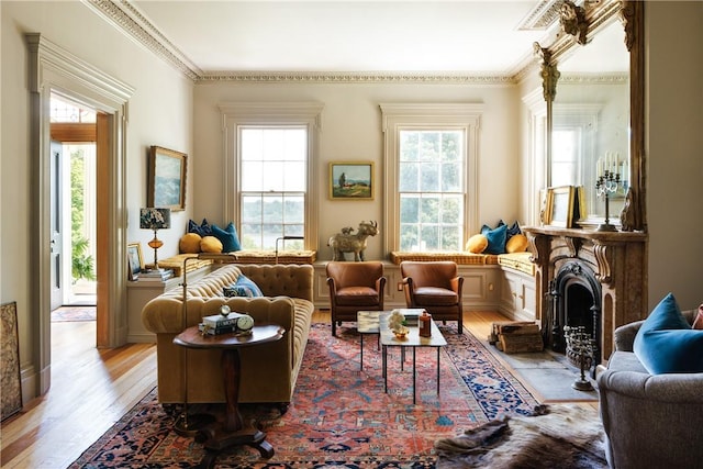 living area with a healthy amount of sunlight, light hardwood / wood-style floors, and ornamental molding