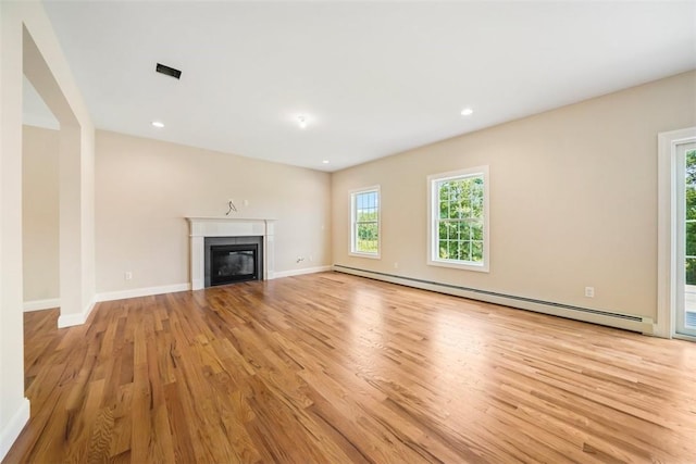 unfurnished living room with light hardwood / wood-style flooring and a baseboard heating unit