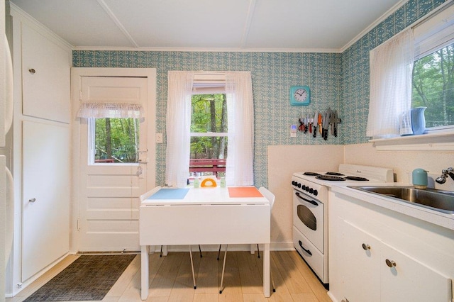 kitchen with white cabinets, white stove, light hardwood / wood-style floors, and sink