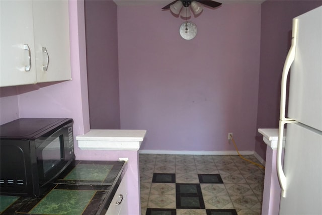 kitchen with ceiling fan, white fridge, and white cabinetry