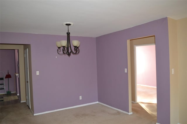 carpeted spare room featuring an inviting chandelier