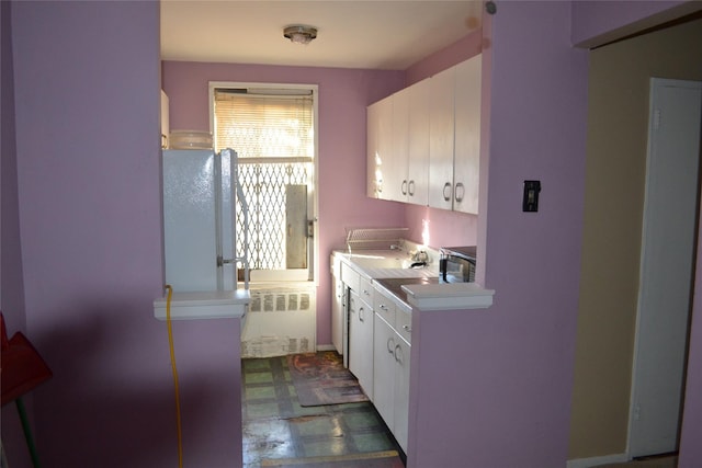 kitchen with refrigerator, radiator heating unit, and white cabinets