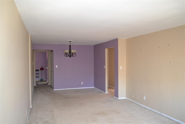 carpeted spare room featuring a chandelier