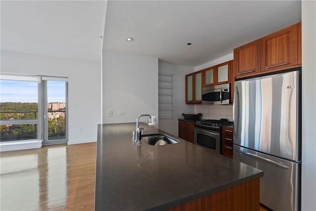 kitchen with decorative backsplash, sink, stainless steel appliances, and light hardwood / wood-style floors