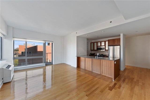 kitchen featuring sink, light wood-type flooring, appliances with stainless steel finishes, tasteful backsplash, and kitchen peninsula