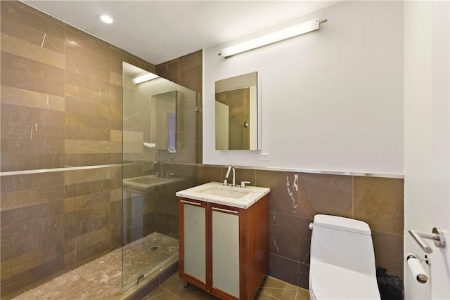 bathroom featuring vanity, tile patterned flooring, toilet, tiled shower, and tile walls