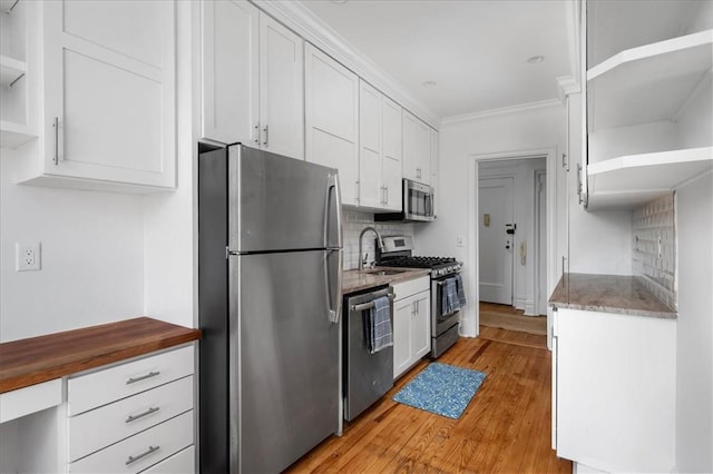 kitchen with tasteful backsplash, stainless steel appliances, crown molding, light hardwood / wood-style floors, and white cabinetry