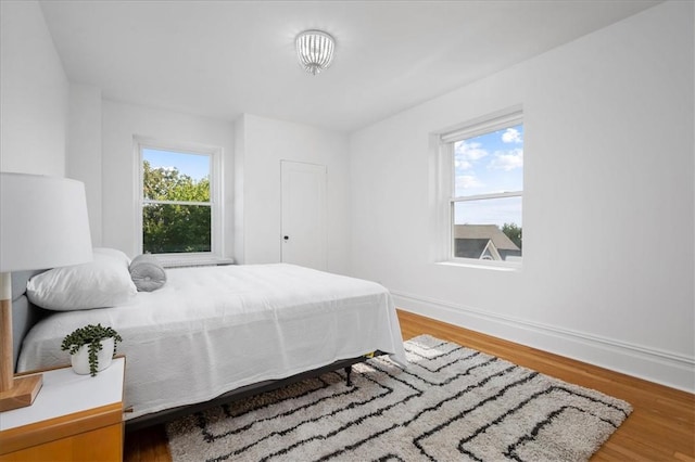 bedroom with multiple windows and hardwood / wood-style flooring