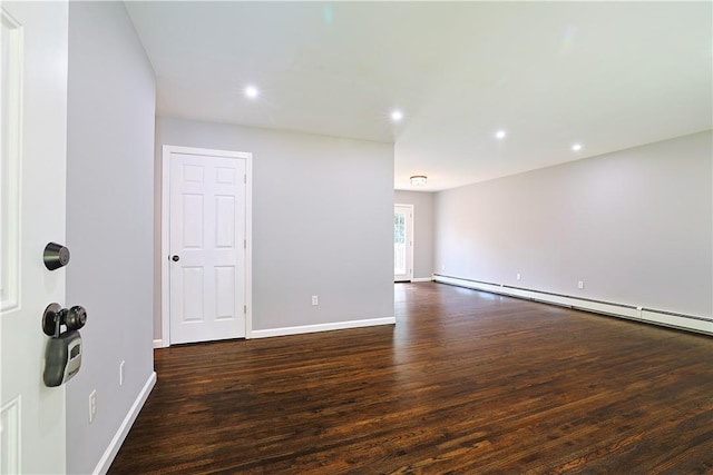 spare room with dark hardwood / wood-style floors and a baseboard heating unit